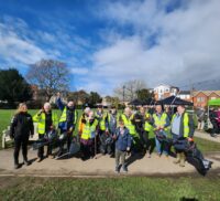 Group of people in high visibility vests holding litter pickers