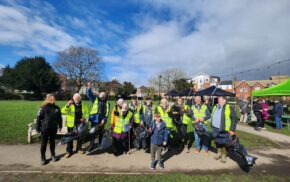 Group of people in high visibility vests holding litter pickers