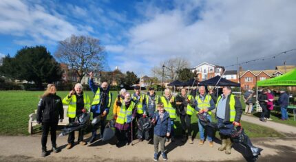 Group of people in high visibility vests holding litter pickers