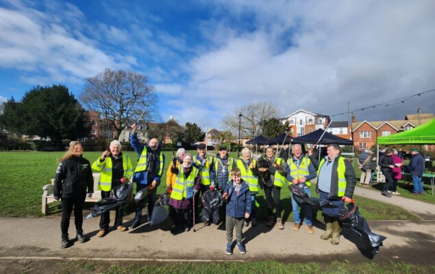 Group of people in high visibility vests holding litter pickers