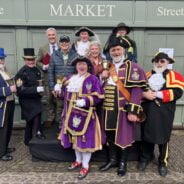 Group of people including town criers in uniform.