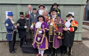 Group of people including town criers in uniform.