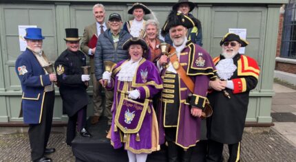 Group of people including town criers in uniform.