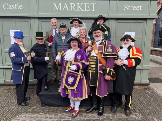 Group of people including town criers in uniform.