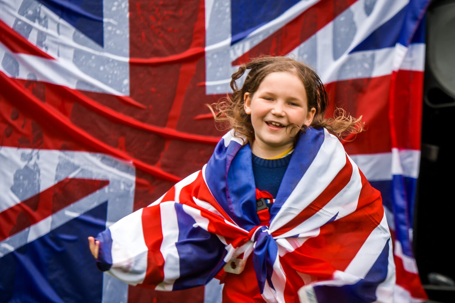 Child with a Union flag draped around her shoulders.
