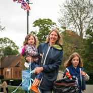 Adult female holding a child and a litter pick. Young girl holding a black sack.