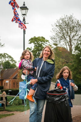 Adult female holding a child and a litter pick. Young girl holding a black sack.