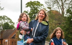 Adult female holding a child and a litter pick. Young girl holding a black sack.