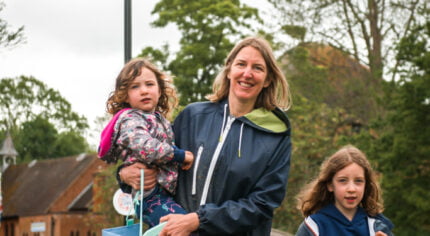 Adult female holding a child and a litter pick. Young girl holding a black sack.