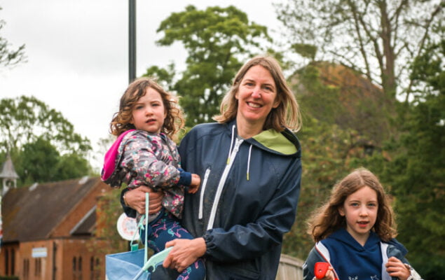 Adult female holding a child and a litter pick. Young girl holding a black sack.