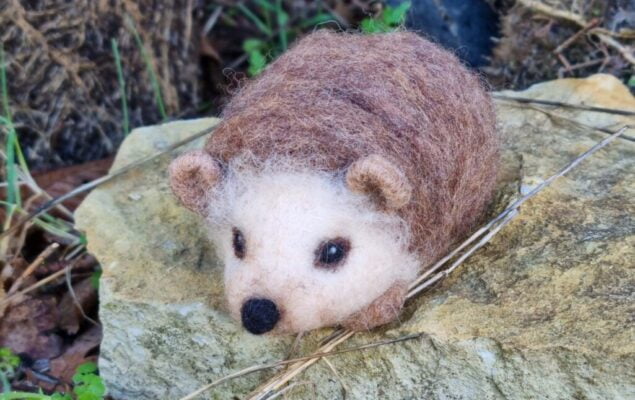 A woodland hedgehog made from felt perched on a rock