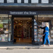 Two females walking past a shop.