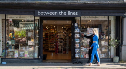 Two females walking past a shop.