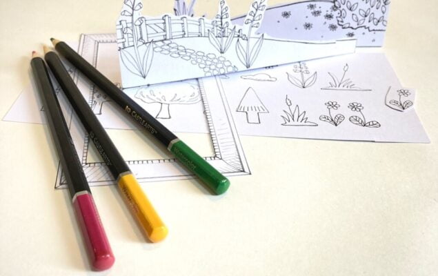 Colouring pencils alongside some black and white drawings of plants and a garden scene