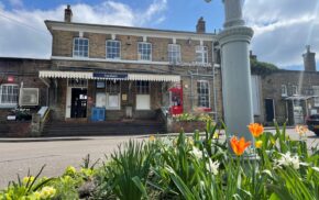 A photo showing Farnham station with flowers blooming in the forefront