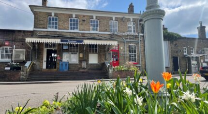 A photo showing Farnham station with flowers blooming in the forefront