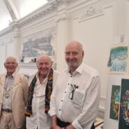 Four men standing in a row smiling.