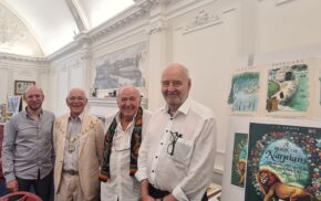 Four men standing in a row smiling.