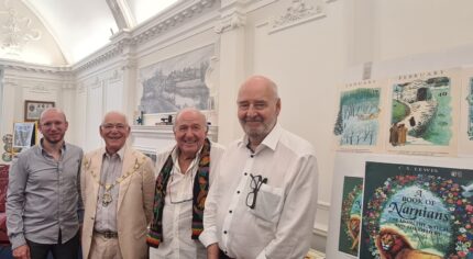 Four men standing in a row smiling.