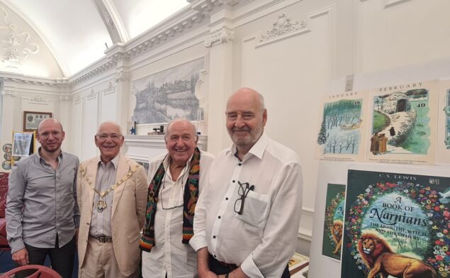 Four men standing in a row smiling.
