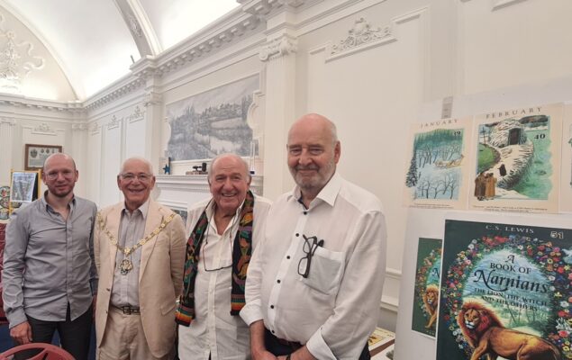 Four men standing in a row smiling.