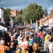 Crowd of people in street. Market stalls in background