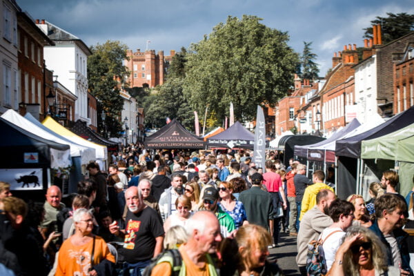 Crowd of people in street. Market stalls in background