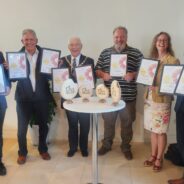 Group of six people holding certificates and awards.