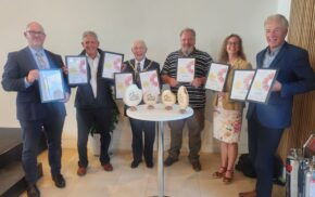 Group of six people holding certificates and awards.