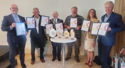 Group of six people holding certificates and awards.
