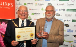 Mayor holding a certificate. Man on right of Mayor holding a glass trophy.