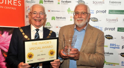 Mayor holding a certificate. Man on right of Mayor holding a glass trophy.