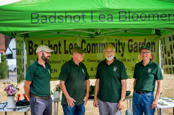 Four males wearing green t-shirts. Standing under a green gazebo.