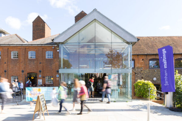 Red brick building with glass porch and people walking around.