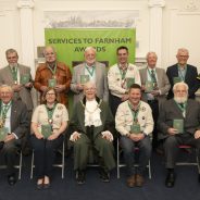 Group of people holding an award. The front row are seated and the back row is standing.