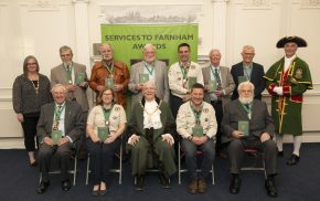 Group of people holding an award. The front row are seated and the back row is standing.