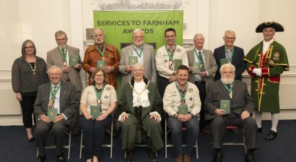 Group of people holding an award. The front row are seated and the back row is standing.