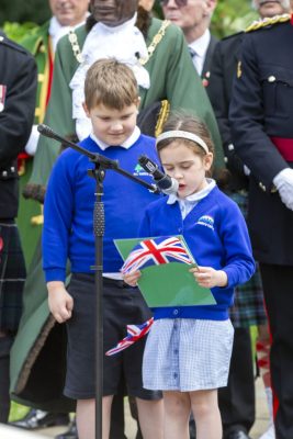 Two school children, one speaking into a microphone