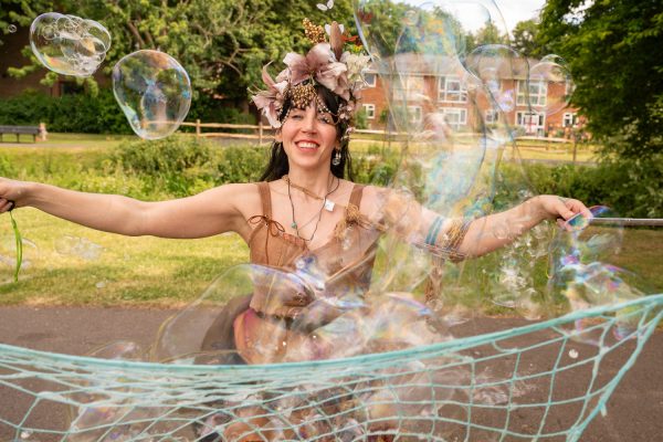Female bubbleologist wearing a floral headdress blowing bubbles