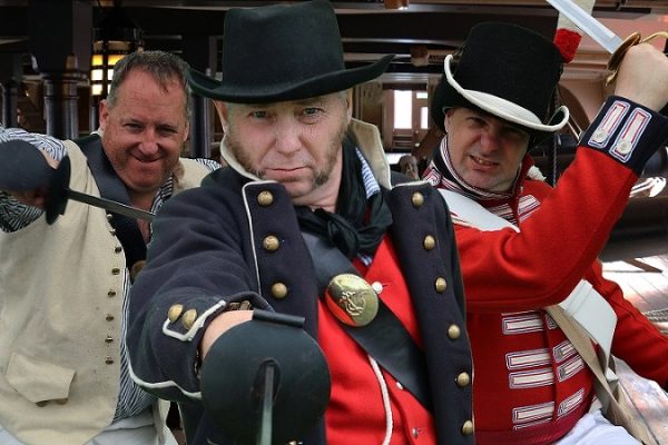 Three men dressed in 18th century naval uniforms
