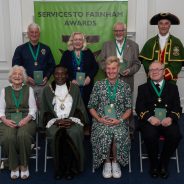 Seven people sitting alongside the Mayor and Town Crier.