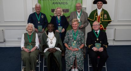 Seven people sitting alongside the Mayor and Town Crier.
