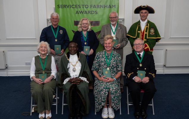 Seven people sitting alongside the Mayor and Town Crier.