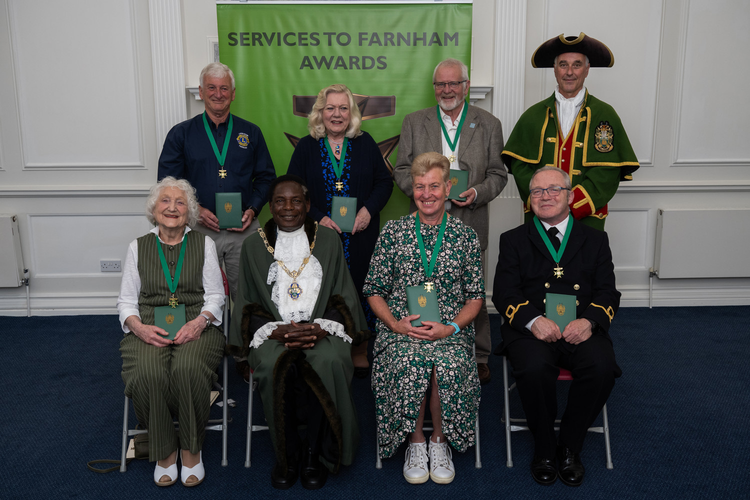 Seven people sitting alongside the Mayor and Town Crier.