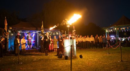 Lighting of a beacon with people in the background.