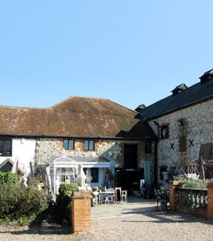 Exterior of white stone building, chairs and tables outside.