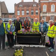 Group of people planting flowers in a large container.