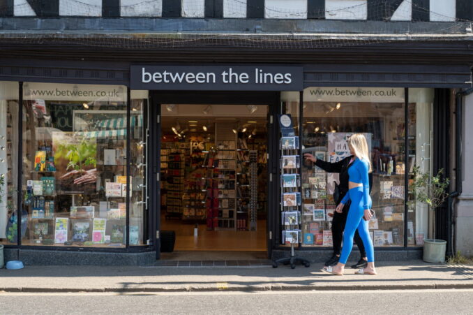 Two females walking past a shop.