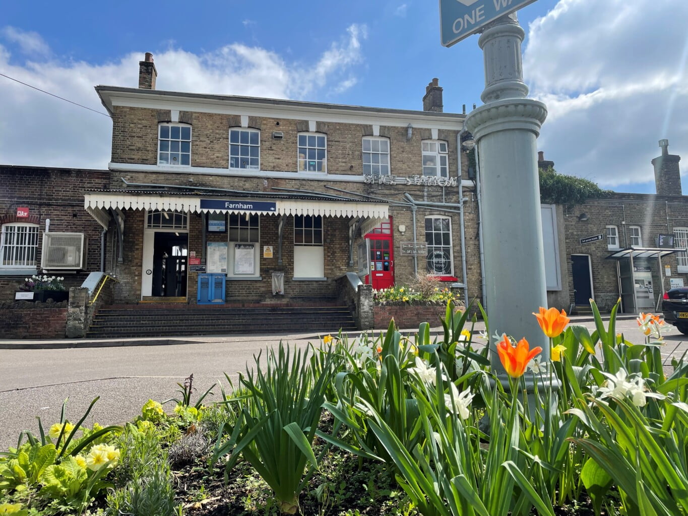 A photo showing Farnham station with flowers blooming in the forefront