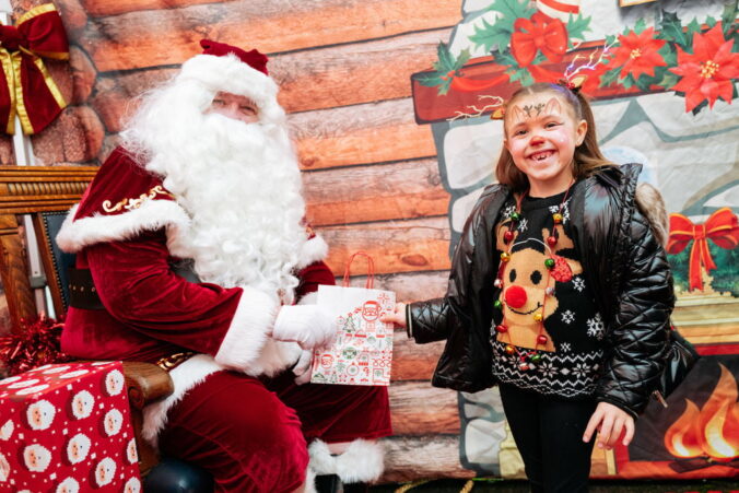 Father Christmas handing a gift to a young girl